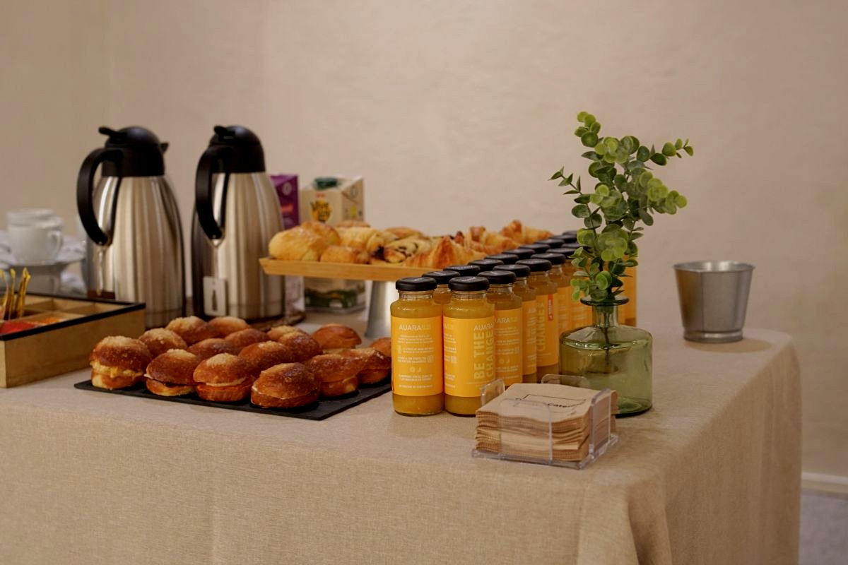 Mesa de desayuno corporativo con mini brioches, zumos AUARA y eucalipto