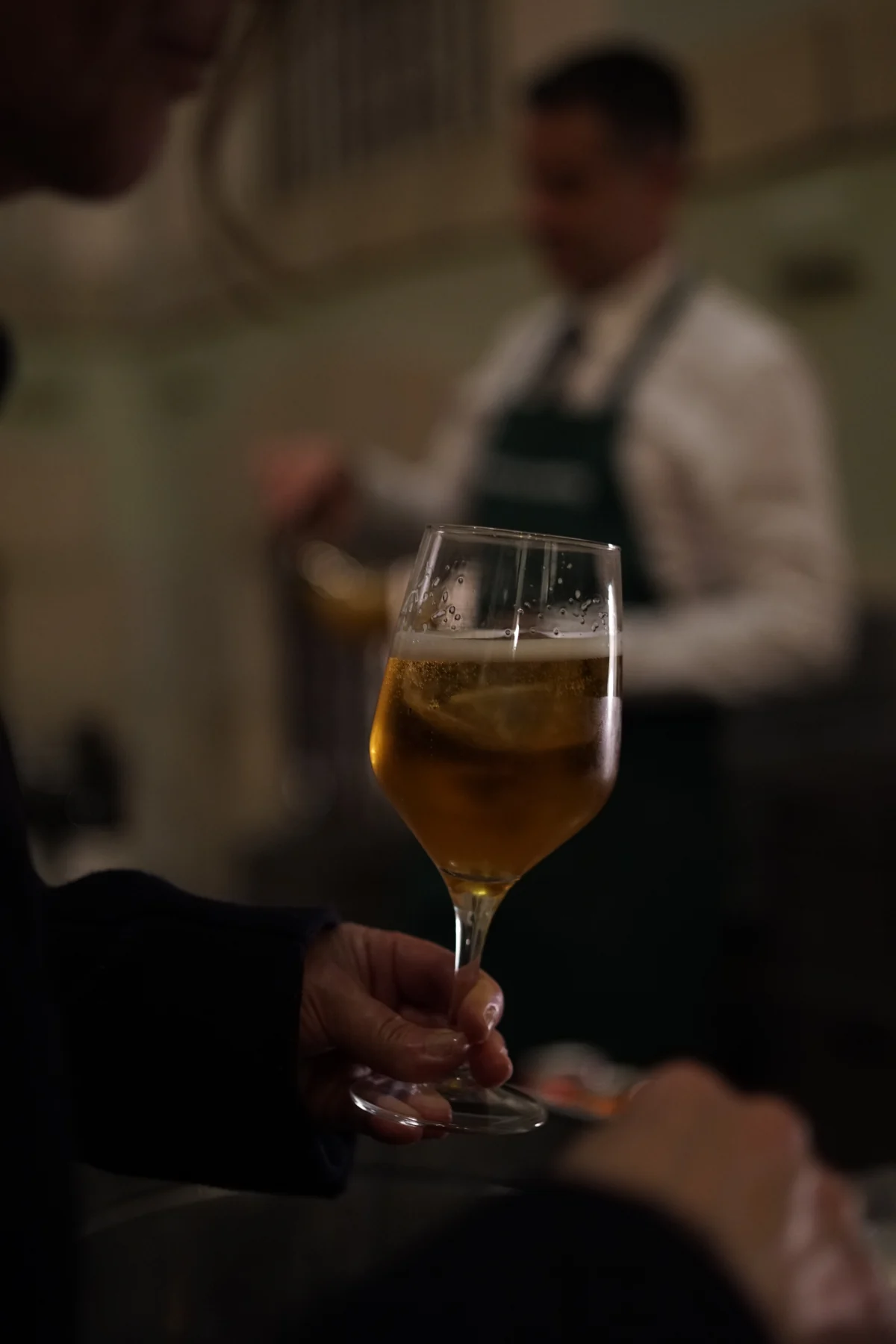 Camarero Duetto al fondo durante un cóctel corporativo en Madrid con copa de cerveza en primer plano