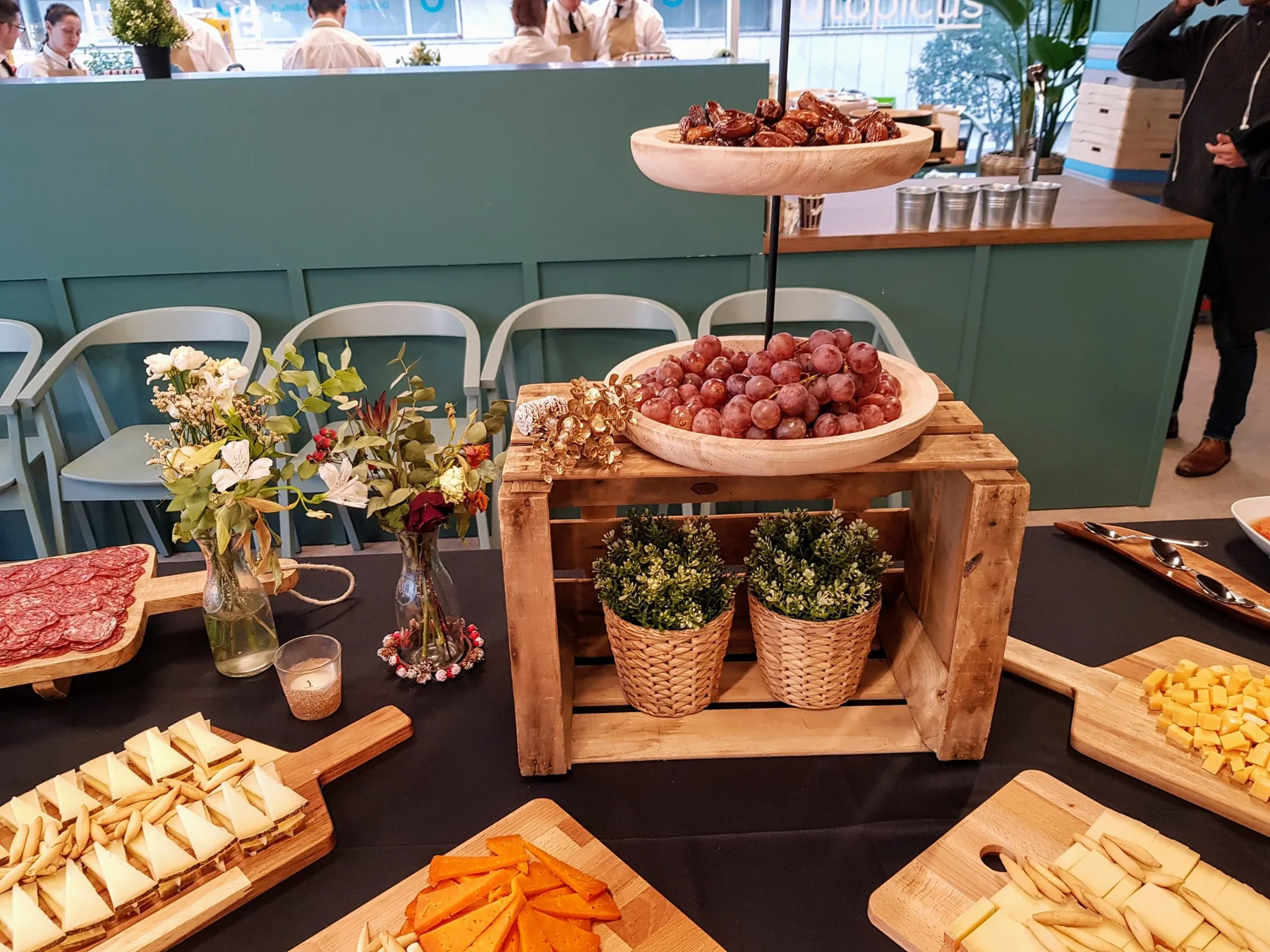Tabla de quesos gourmet con uvas, embutidos y dados de queso en montaje de evento
