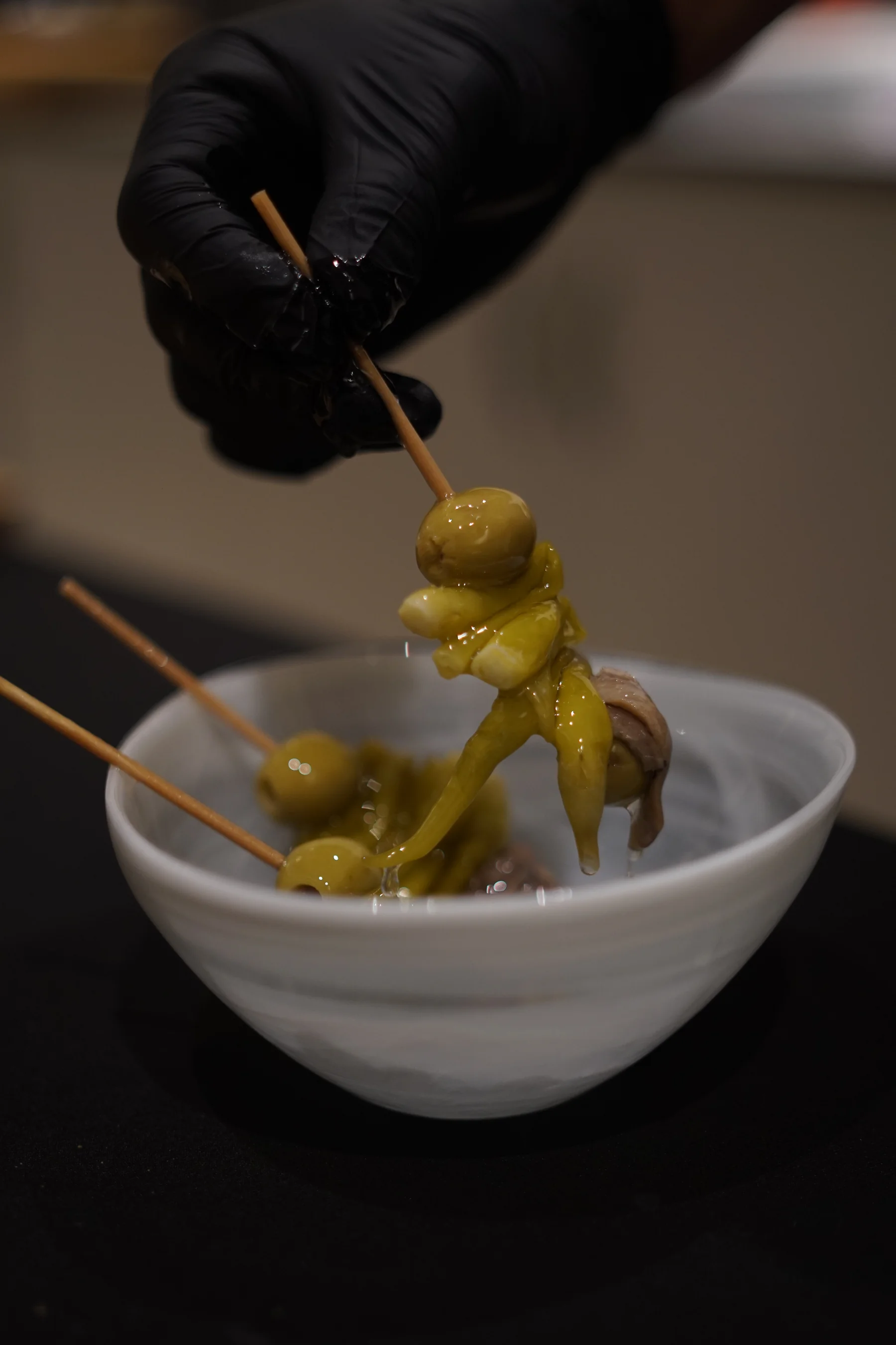 Preparación de pinchos de olivas con guante en cocina