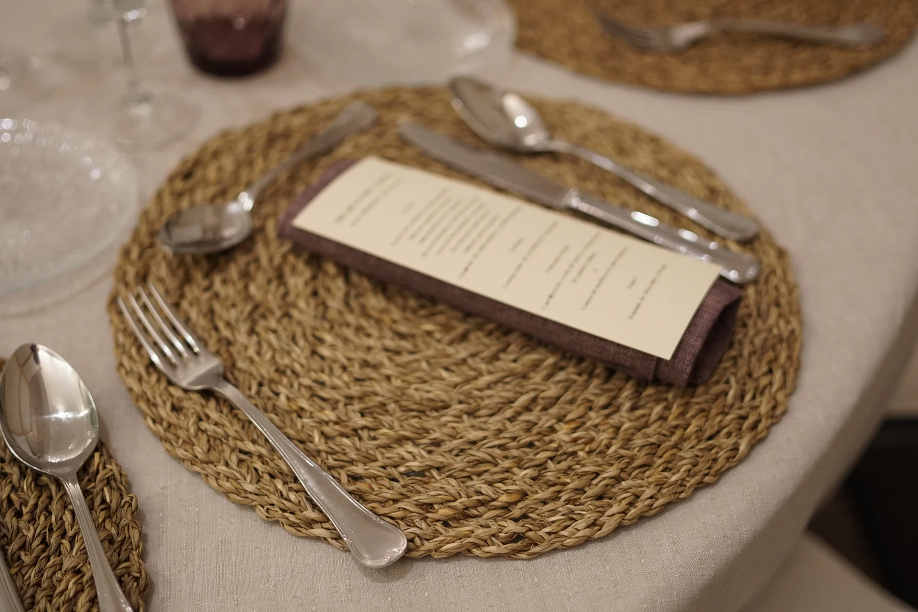 Detalle de mesa de comunión con menú impreso, cubertería y mantel individual