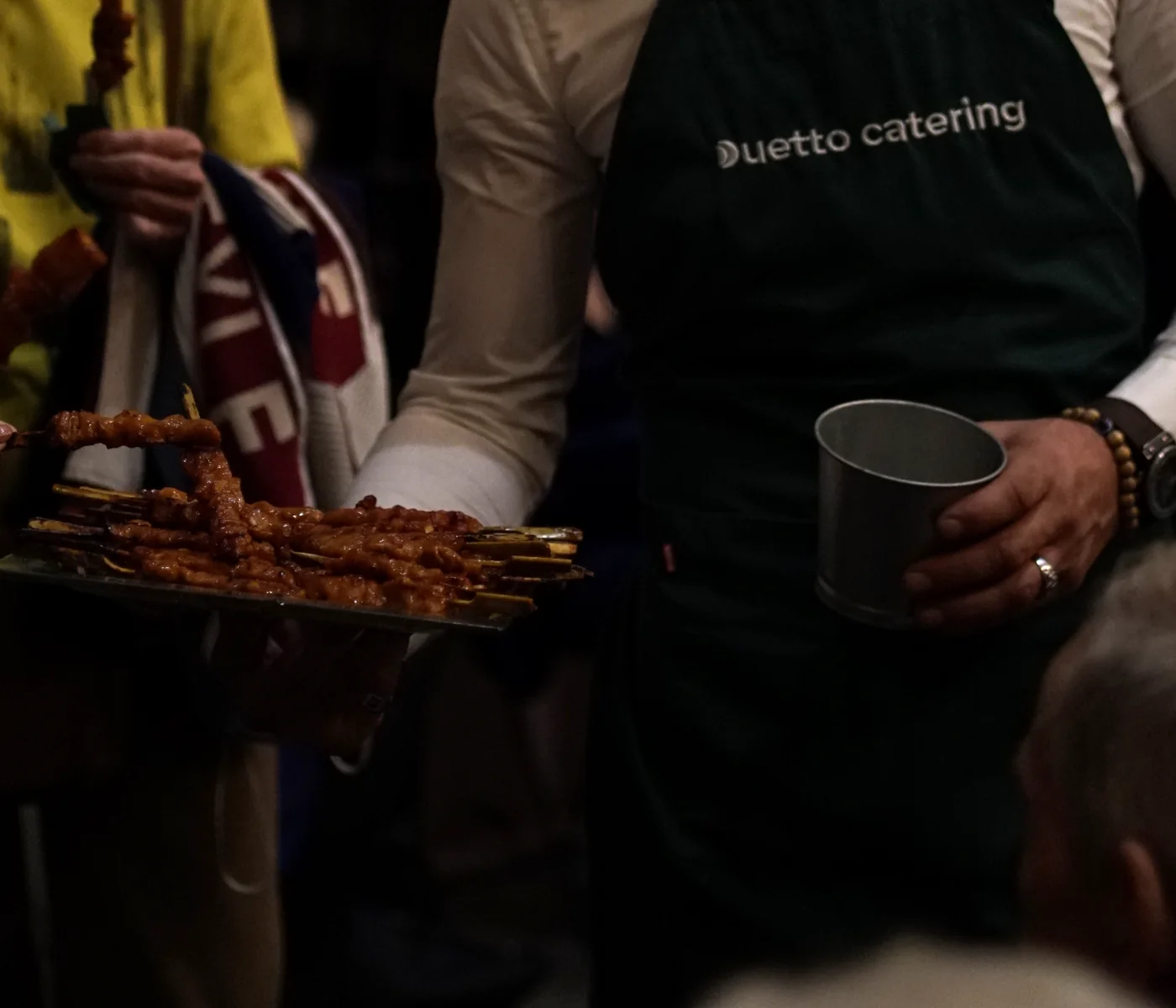 Camarero Duetto Catering sirviendo bandeja de brochetas en vino español corporativo